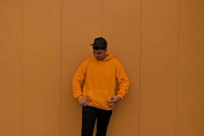 Young man standing against orange wall