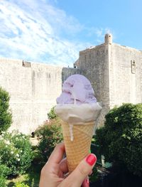 Close-up of woman holding ice-cream against building