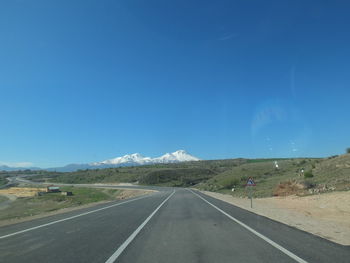 Road by mountain against blue sky