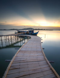 Pier over sea against sky during sunset