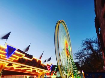 Low angle view of illuminated ferris wheel against buildings