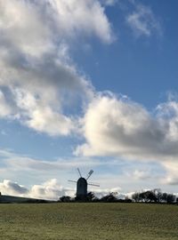 Traditional windmill on field against sky