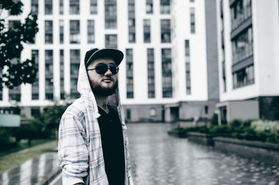 Young man wearing sunglasses while standing against building