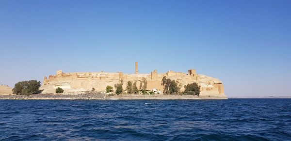 Castle by sea against clear blue sky