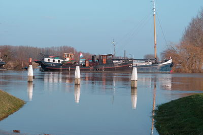 Boats moored at harbor against clear sky