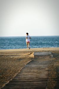 Full length of man standing on beach against clear sky