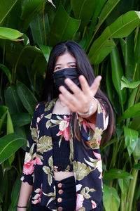 Portrait of young woman standing against plants