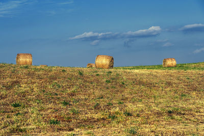 Hay bales on field against sky