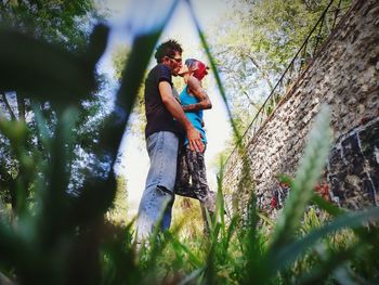 Couple kissing on field seen through grass