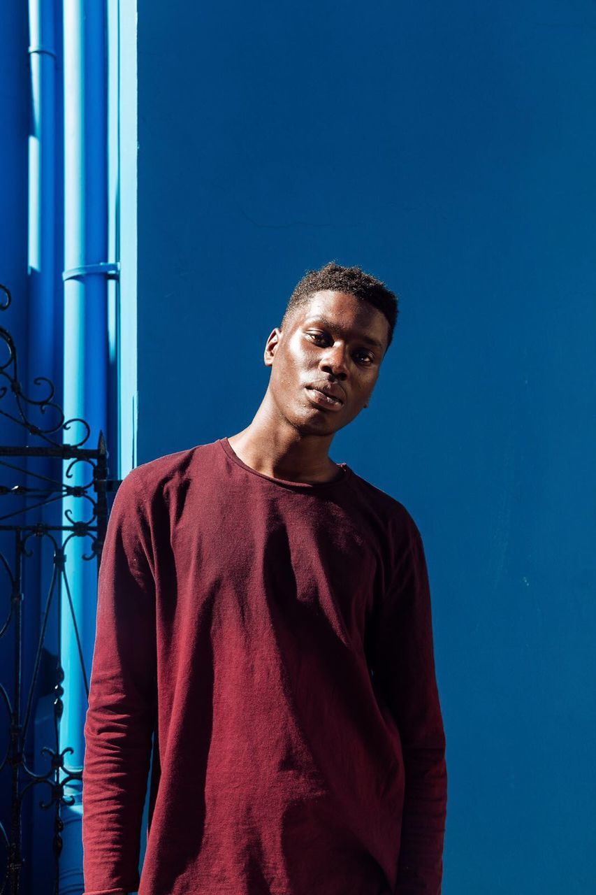 LOW ANGLE VIEW OF YOUNG MAN LOOKING AWAY