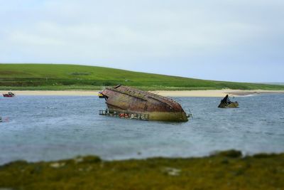 Shipwreck in sea against sky