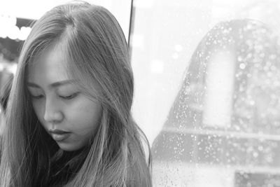 Close-up of young woman against frosted glass