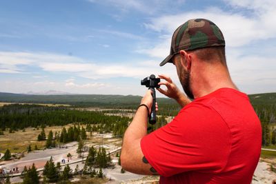 Rear view of man photographing against sky