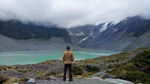Rear view of woman standing on mountain against sky