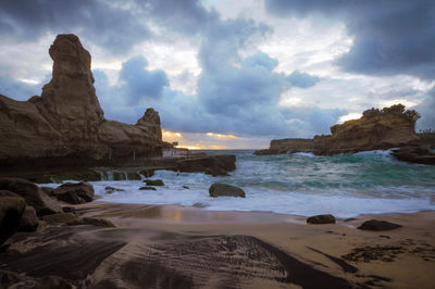 Scenic view of rocks on beach against sky
