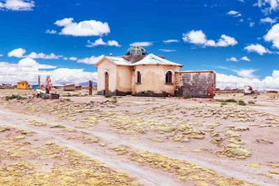 Buildings on field against blue sky