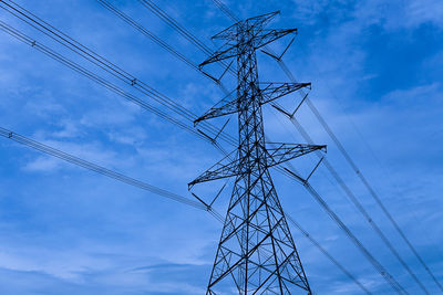 Low angle view of electricity pylon against blue sky