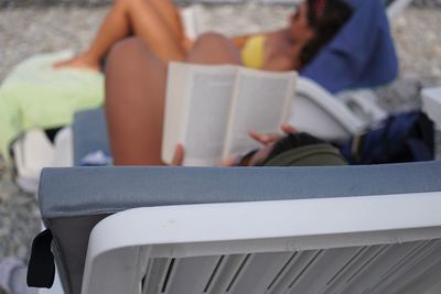 High angle view of people reading books while resting on chairs at beach