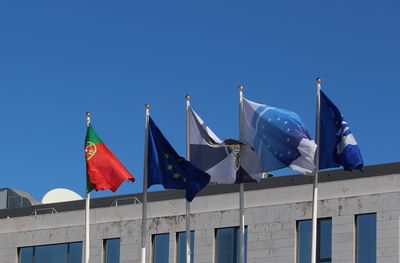 Low angle view of flags against clear blue sky