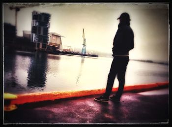 Silhouette man standing by sea against sky during sunset