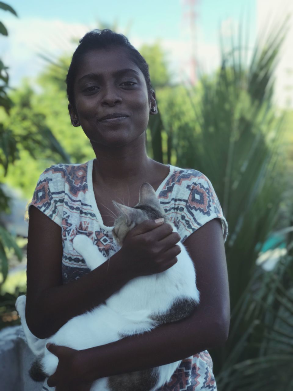 one person, front view, real people, looking at camera, outdoors, day, one animal, smiling, standing, portrait, young adult, young women, animal themes, close-up, nature, mammal, people