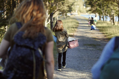 Rear view of girl walking along dirt road