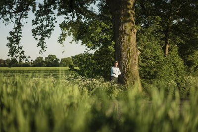 Businessman leaning on tree