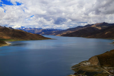 Scenic view of lake and mountains against cloudy sky