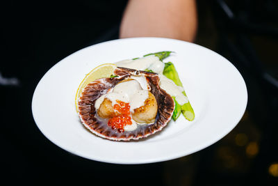 Grilled scallops in a shell with red caviar and asparagus under a sauce, luxury catering