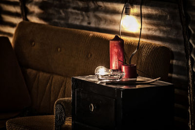 Illuminated light bulb on table by sofa