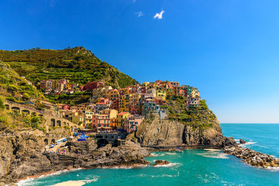 Buildings on rock formation by sea against sky at manorola