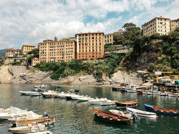 Sailboats moored in sea against buildings in city