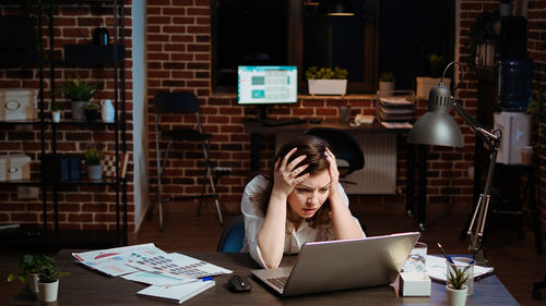 Young woman using laptop while sitting at cafe