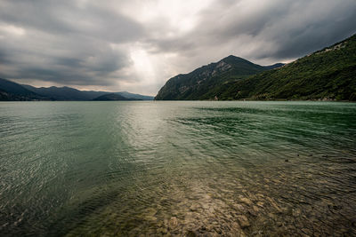 Scenic view of sea by mountains against sky