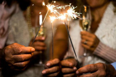 Midsection of woman holding sparkler at home