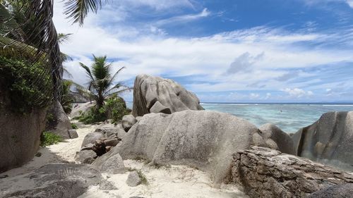 Rocks on shore by sea against sky