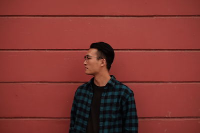 Young man standing against brown wall