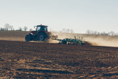 Tractor with plow at the agricultural field . tractor plowing a field with dust