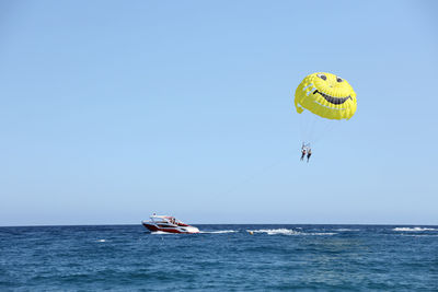 Low angle view of person paragliding over sea against clear sky