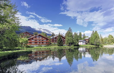 Houses by lake and buildings against sky