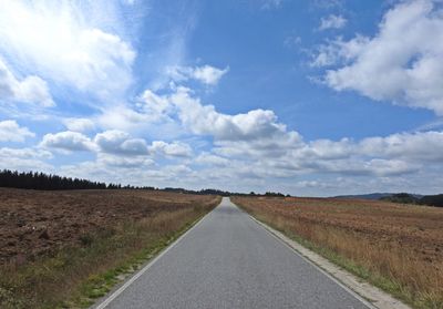 Road amidst field against sky