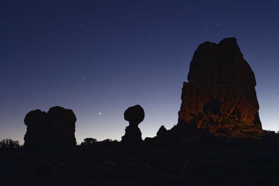 Silhouette rock formations against sky at night