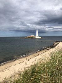 Lighthouse by sea against sky