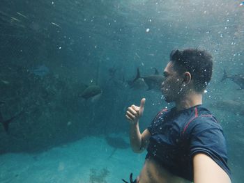 Man with thumbs up sign swimming in sea