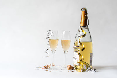 Two champagne glasses and bottle and against white background.