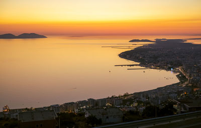 High angle view of townscape by sea against sky during sunset