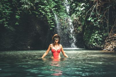 Portrait of woman standing in river at forest