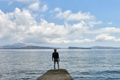 Rear view of man looking at sea against sky