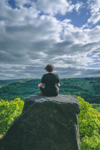 Rear view of man sitting on rock