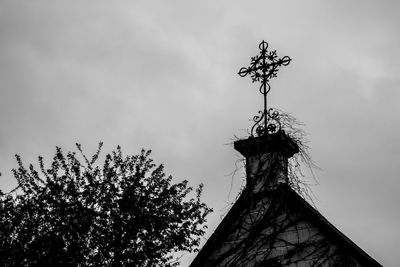 Low angle view of weather vane against sky